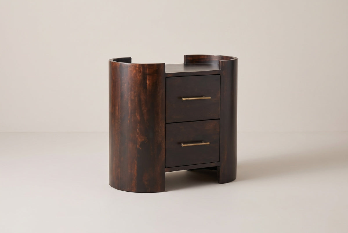 The Macomer nightstand in dark mocha mango: two half-round end columns with low curved rims, two drawers with brass bar pulls between them, three-quarter view on a light studio backdrop