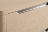Close-up of the Mandas nightstand: light elm veneer with a brushed nickel scoop cut into the top edge of a drawer