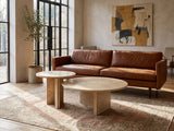 Mantova Gold Beige Marble Nesting Coffee Tables, Set of 2 seen from the side, on a vintage rug in front of a leather sofa in an industrial loft
