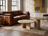 Mantova Gold Beige Marble Nesting Coffee Tables, Set of 2 on a vintage rug in front of a leather sofa in an industrial loft