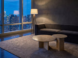 Mantova Gold Beige Marble Nesting Coffee Tables, Set of 2 on a wool rug in front of a velvet sofa in a city penthouse at blue hour