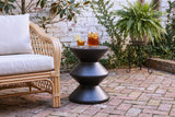 Marineo black concrete zigzag side table with a pitcher of iced tea and a glass beside a rattan armchair in a Savannah, Georgia courtyard, a whitewashed brick wall with creeping fig and herringbone brick paving (chair and decor not included)