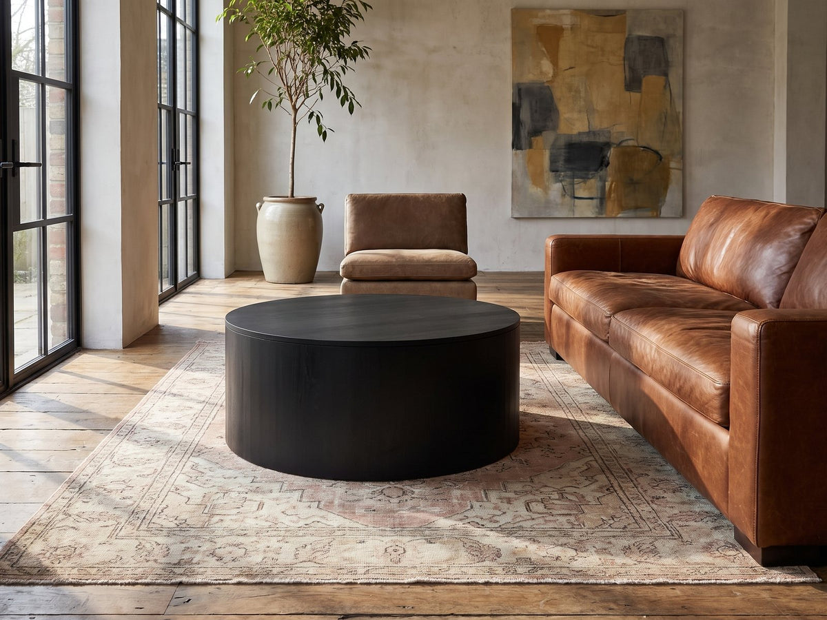 Marostica Black Mango Drum Coffee Table on a vintage rug in front of a leather sofa in an industrial loft