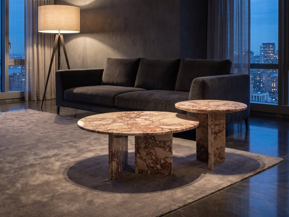 Marzamemi Rosa Marble Nesting Coffee Tables, Set of 2 on a wool rug in front of a velvet sofa in a city penthouse at blue hour