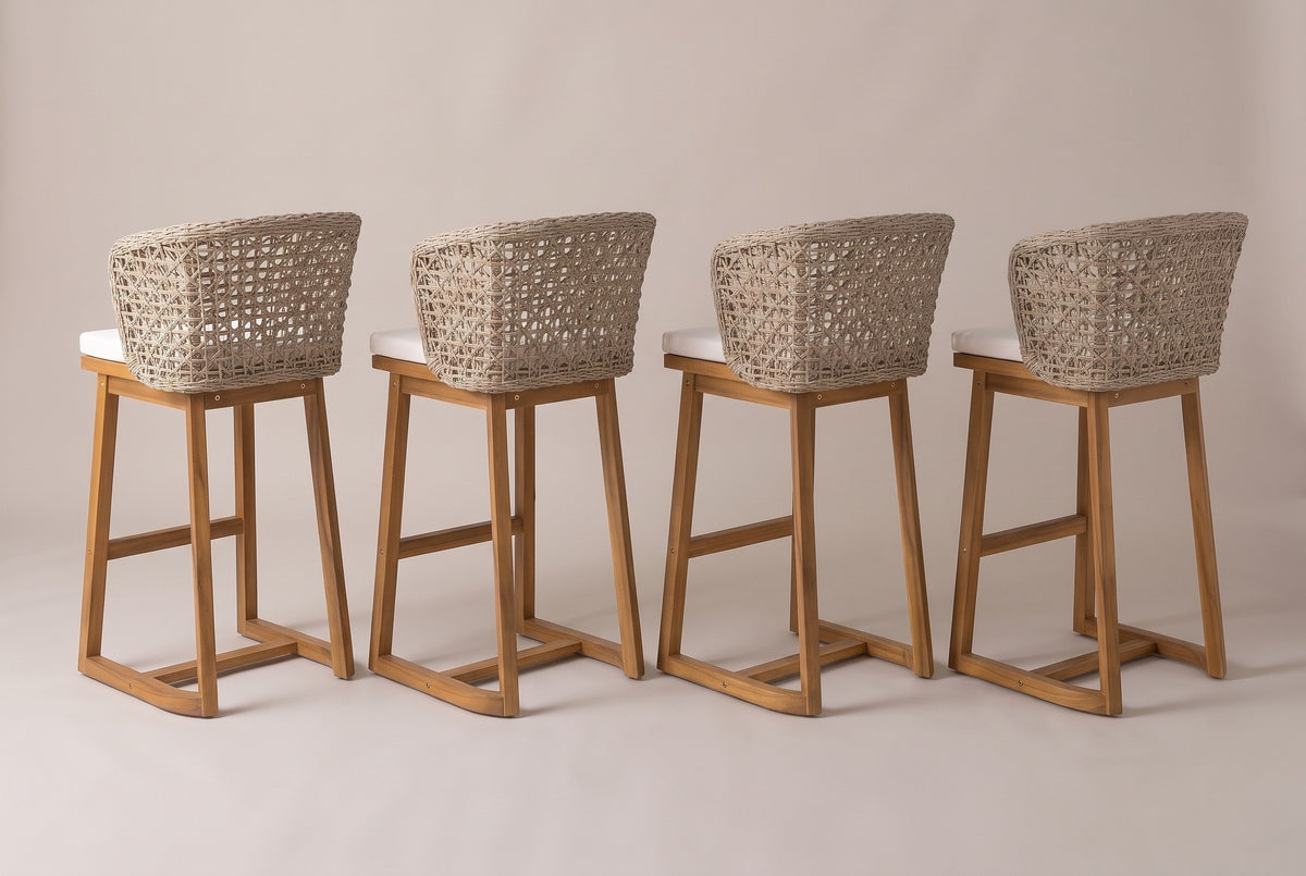 The four Mascali stools from behind: the curved open-lattice wicker backs, the acacia legs and the rounded back corners of the sled runners