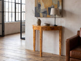 Massafra Burl Half-Moon Console Table against a plaster wall in an industrial loft