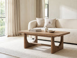 Matelica Reclaimed Pine Trestle Coffee Table styled with books, a vase and a stone bowl in front of a cream sofa in a bright plaster room