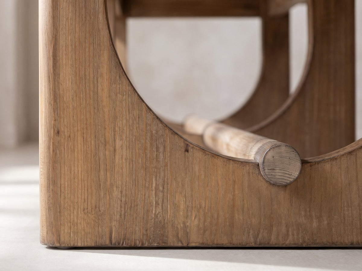 Close-up of the Matelica Reclaimed Pine Trestle Coffee Table: the half-circle opening of an end panel and the round stretcher passing through it