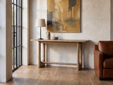 Matelica Reclaimed Pine Trestle Console Table against a plaster wall in an industrial loft