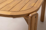 Close-up of a rounded corner of the Mazara dining table: lengthwise acacia slats, the curved border frame with its rounded edge and the corner leg with a small bolt cap