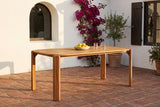 Mazara acacia dining table on a terracotta tile terrace in Santa Barbara, a white lime-washed wall with an arched window, bougainvillea and a potted olive tree behind (chairs not included)