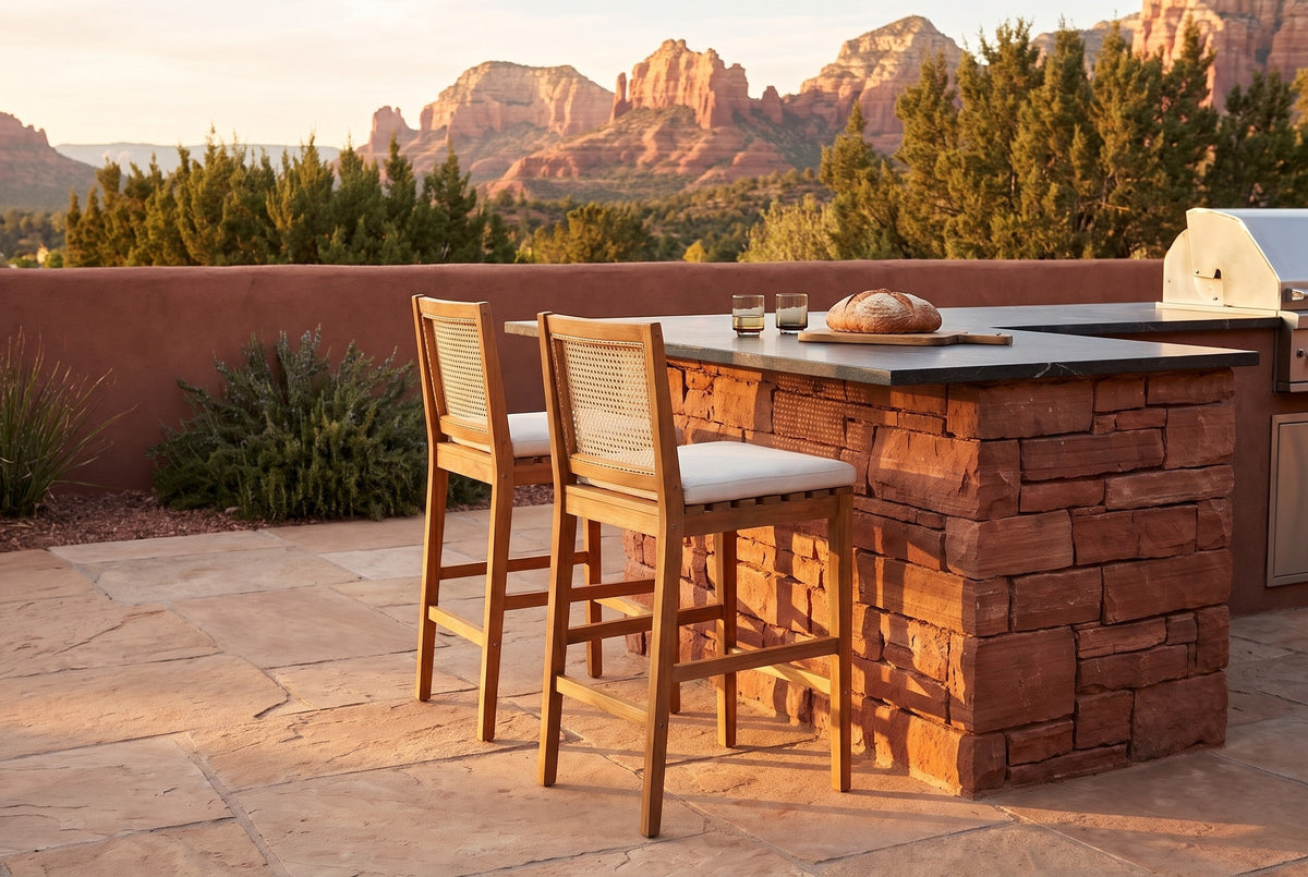 Two Mazzarino acacia bar stools with cane backs tucked at the end of a red sandstone outdoor kitchen with a soapstone top on a Sedona terrace at golden hour, red rock buttes behind (outdoor kitchen not included)