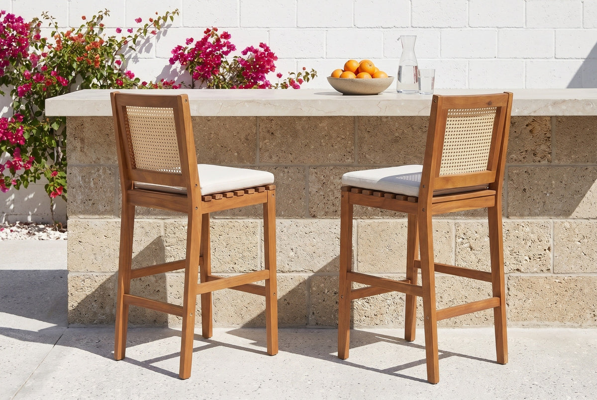 Two Mazzarino acacia bar stools at a coquina stone outdoor kitchen with a limestone top in a walled St. Augustine garden, bougainvillea on a white wall behind (outdoor kitchen not included)