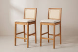 The two Mazzarino bar stools side by side, both turned the same way: cane backs, pale beige cushions, square legs and the low footrest rails