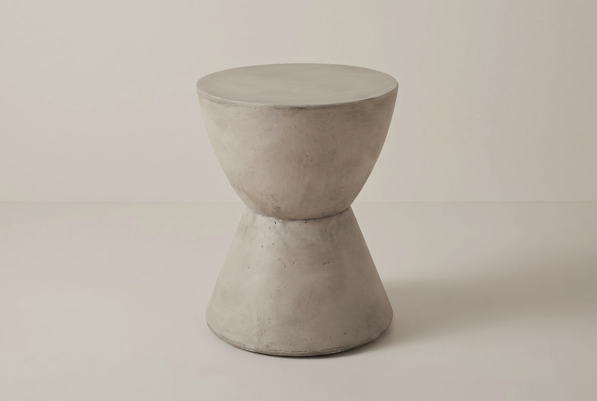 The Mazzaro light grey concrete hourglass side table, three-quarter view on a light studio backdrop