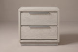 The Melfi nightstand in wire-brushed gray oak, front view on a warm studio backdrop: two stacked drawers with long brushed metal pulls above a low plinth