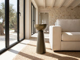 Melpignano Antique Gold Iron Pedestal Side Table beside a linen sofa in a poolside villa