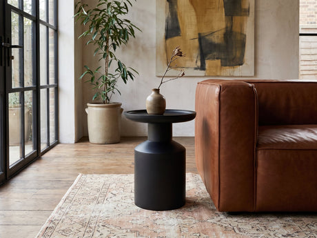 Mesoraca Black Mango Pedestal Side Table beside a leather sofa in an industrial loft