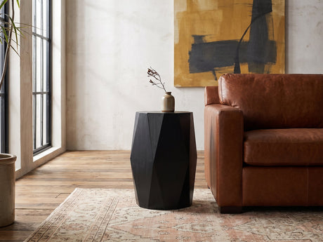 Miglionico Black Mango Wood Faceted Drum Side Table beside a leather sofa in an industrial loft