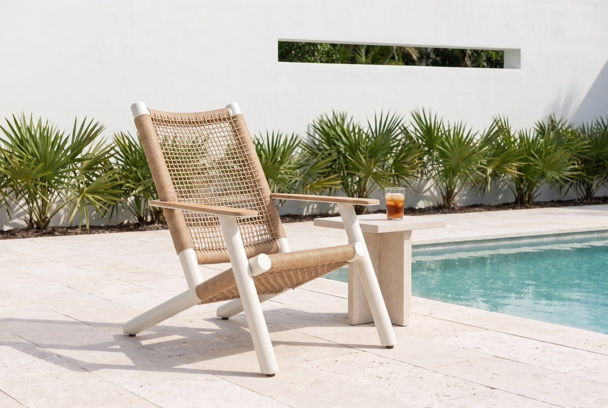 Militello lounge chair on pale shellstone pavers beside a pool at a modern Sarasota house, a white stucco wall and palmettos behind (side table not included)