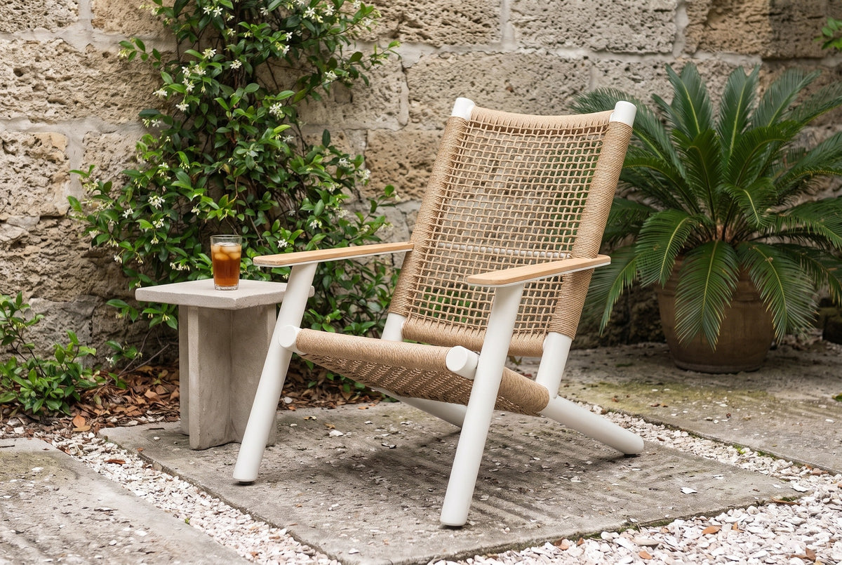Militello lounge chair in a St. Augustine courtyard with a coquina stone wall, star jasmine and a potted sago palm (side table not included)