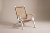 The Militello lounge chair: white aluminum frame, natural beige wicker seat and open-grid back, teak arms, three-quarter view on a light studio backdrop