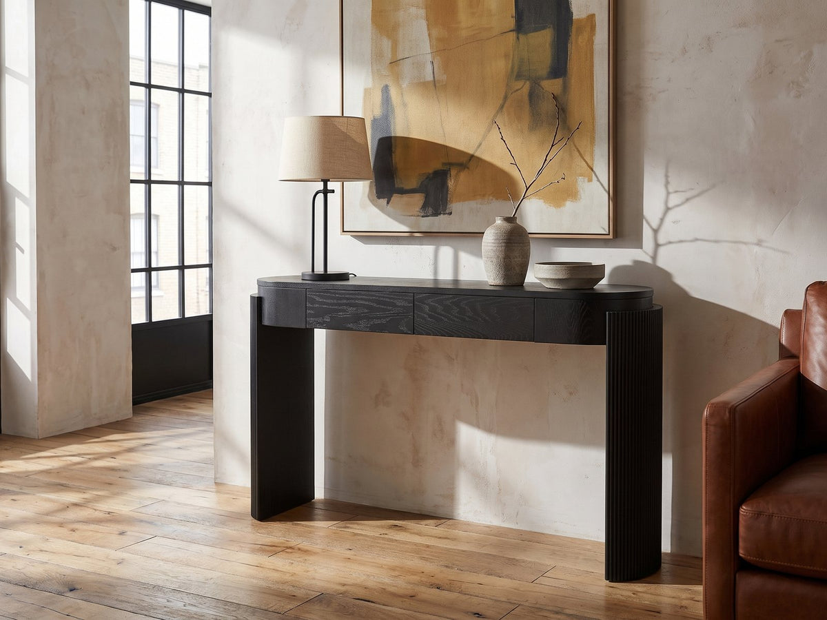 Minervino Black Oak Fluted Racetrack Console Table against a plaster wall in an industrial loft
