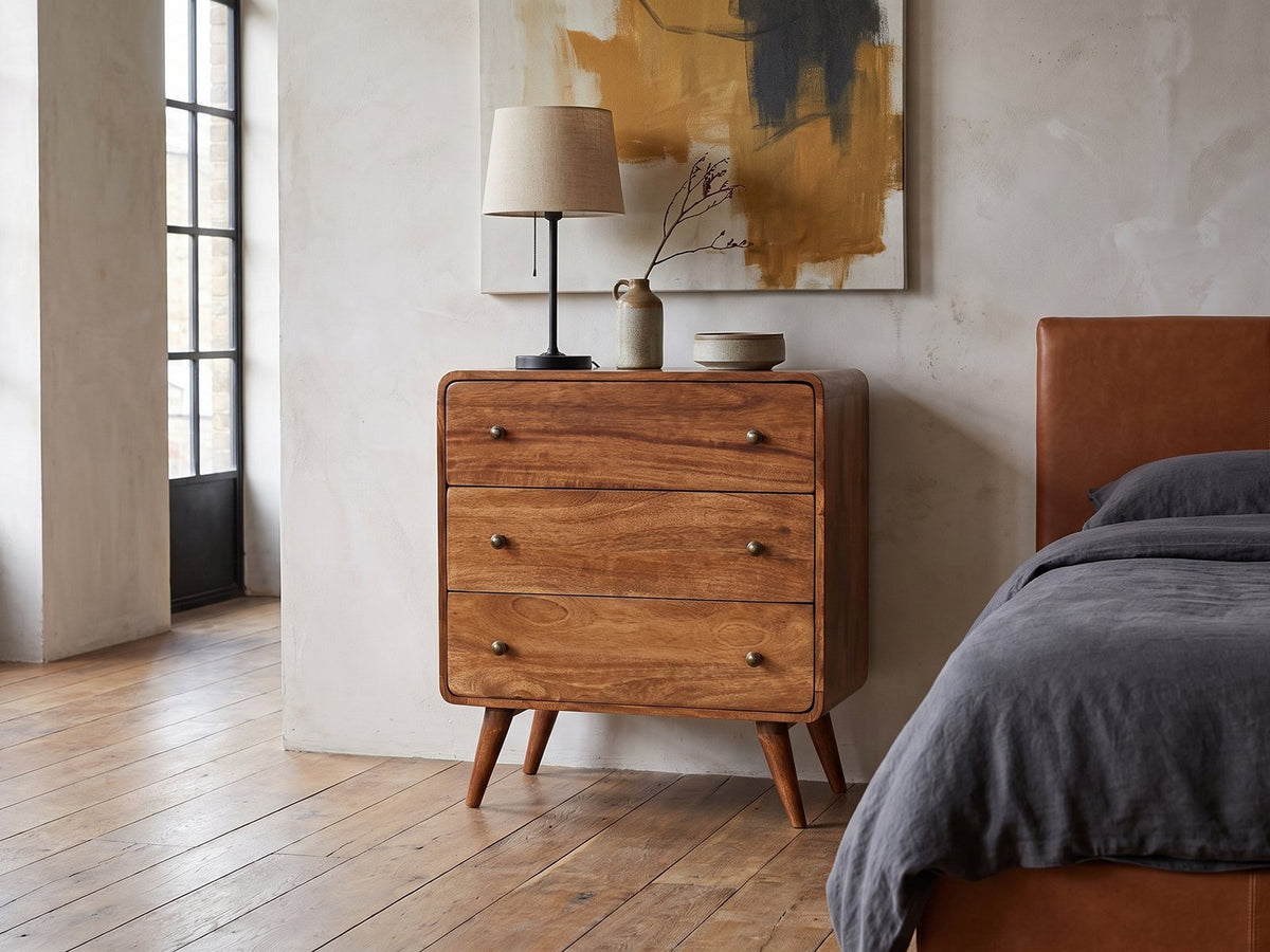 Mira 28-Inch Honey Caramel Solid Mango 3-Drawer Chest against a plaster wall in an industrial loft bedroom