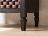 Close-up of the Mirano 33-Inch Velvet Mocha Carved Mango 3-Drawer Chest: a turned and tapered leg under the square corner of the carved chest