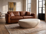 Modica Cream Fiberglass Pebble Coffee Table on a vintage rug in front of a leather sofa in an industrial loft