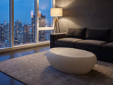 Modica Cream Fiberglass Pebble Coffee Table on a wool rug in front of a velvet sofa in a city penthouse at blue hour