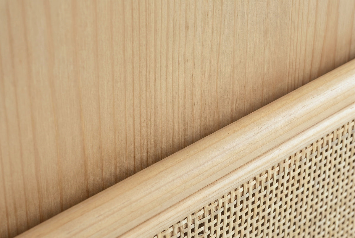 Close-up of the natural pine on the Mogoro nightstand: straight grain on the side panel beside a half-round moulding and a cane panel