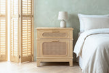 Mogoro pine and cane nightstand against a sage-green plaster wall in a Savannah bedroom with a herringbone floor and wooden shutters