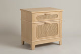 The Mogoro nightstand in natural pine with two cane drawers, wood bar pulls and four short tapered legs, three-quarter view on a light studio backdrop