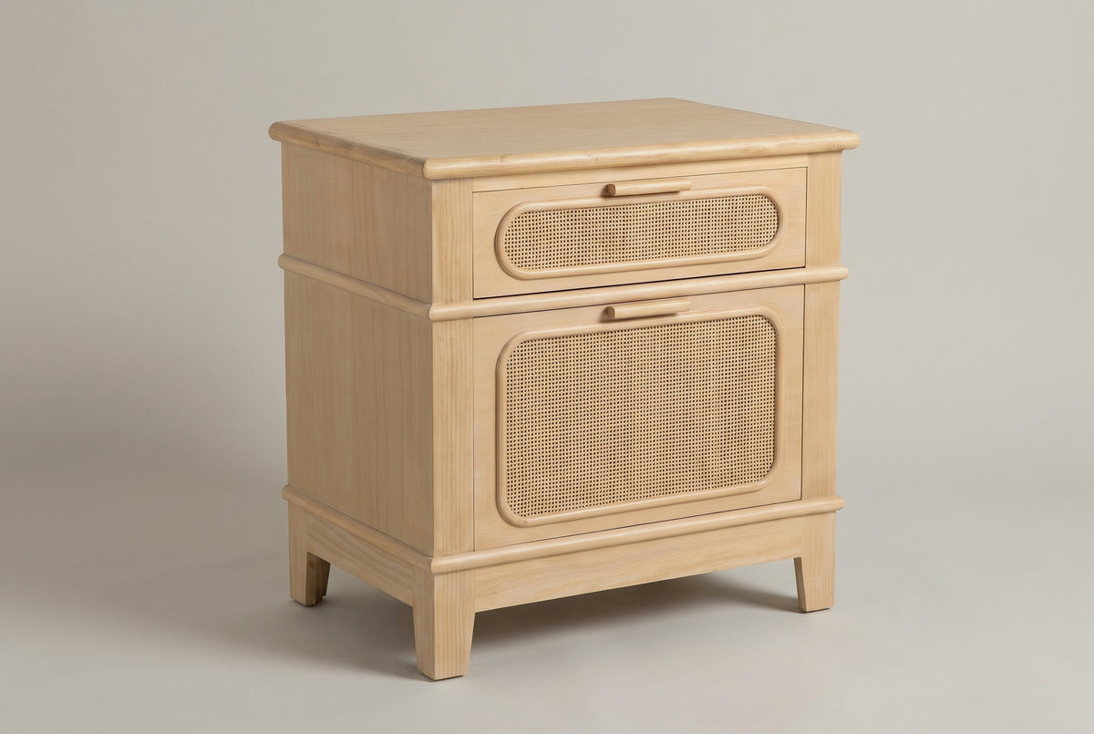 The Mogoro nightstand in natural pine with two cane drawers, wood bar pulls and four short tapered legs, three-quarter view on a light studio backdrop