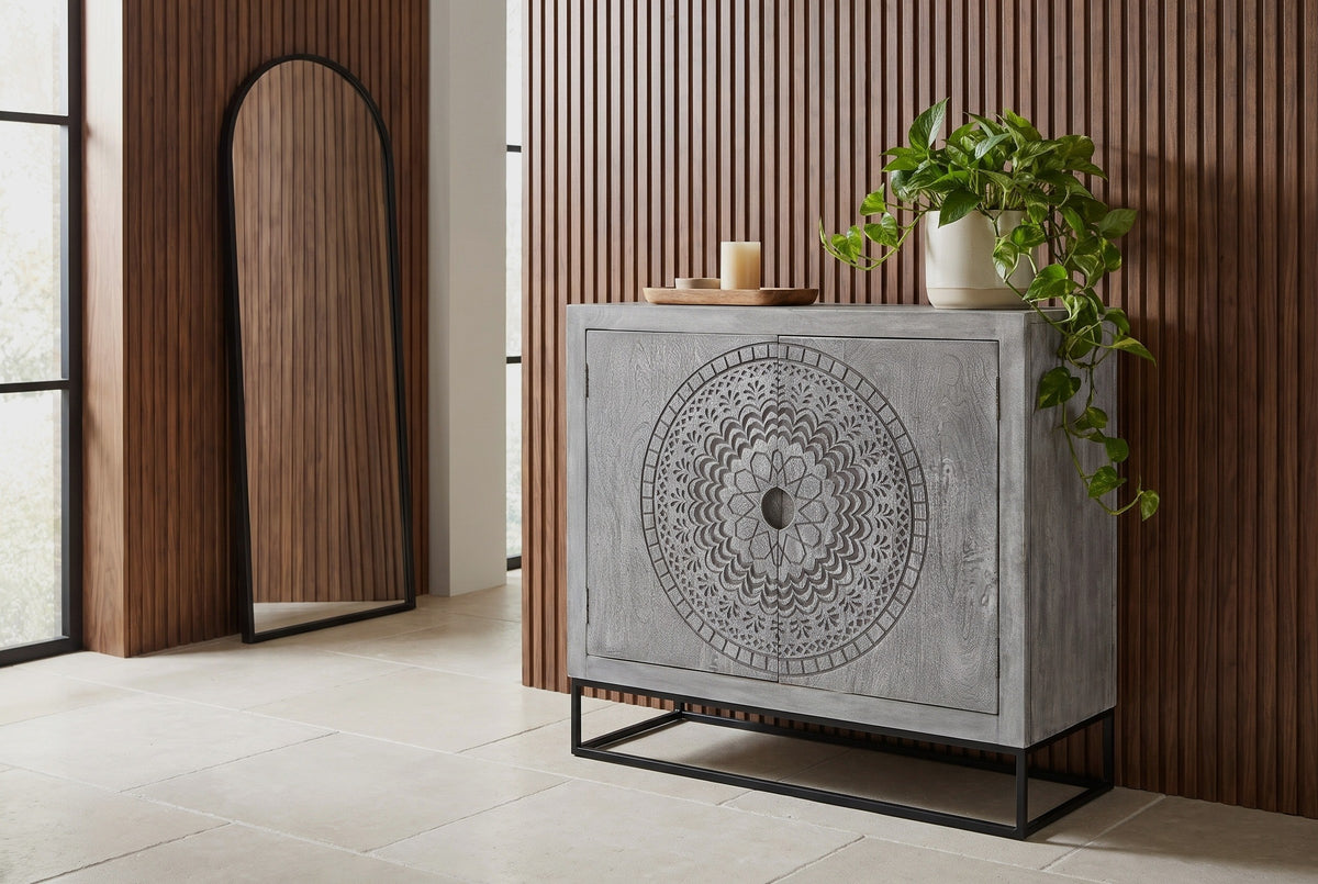 Molfetta carved grey accent cabinet with a trailing plant on top, against a fluted walnut slat wall in an Austin entryway with a limestone floor