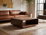 Molveno Walnut-Tone Wood Veneer Coffee Table seen from the side, on a vintage rug in front of a leather sofa in an industrial loft