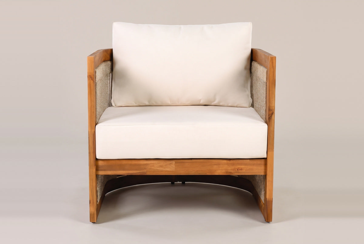 The Mondello club chair seen from the front: the ivory seat and back cushions, the acacia seat rail and the open arch under the seat