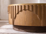 Close-up of the Mondovi 36-Inch Round Carved Limed Ash Drum Coffee Table: stepped ash slats ending along the curve of a carved half-moon arch