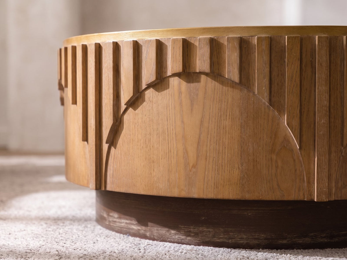 Close-up of the Mondovi 36-Inch Round Carved Limed Ash Drum Coffee Table: stepped ash slats ending along the curve of a carved half-moon arch