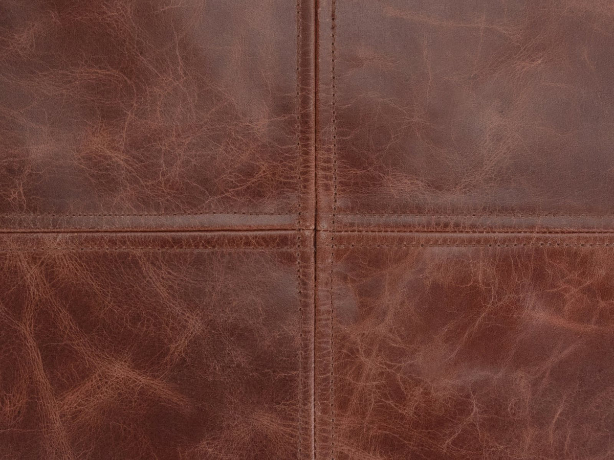 Close-up of the Moneglia Distressed Brown Top-Grain Buffalo Leather Round Pouf: the four-panel round top, its two topstitched seams crossing at the centre