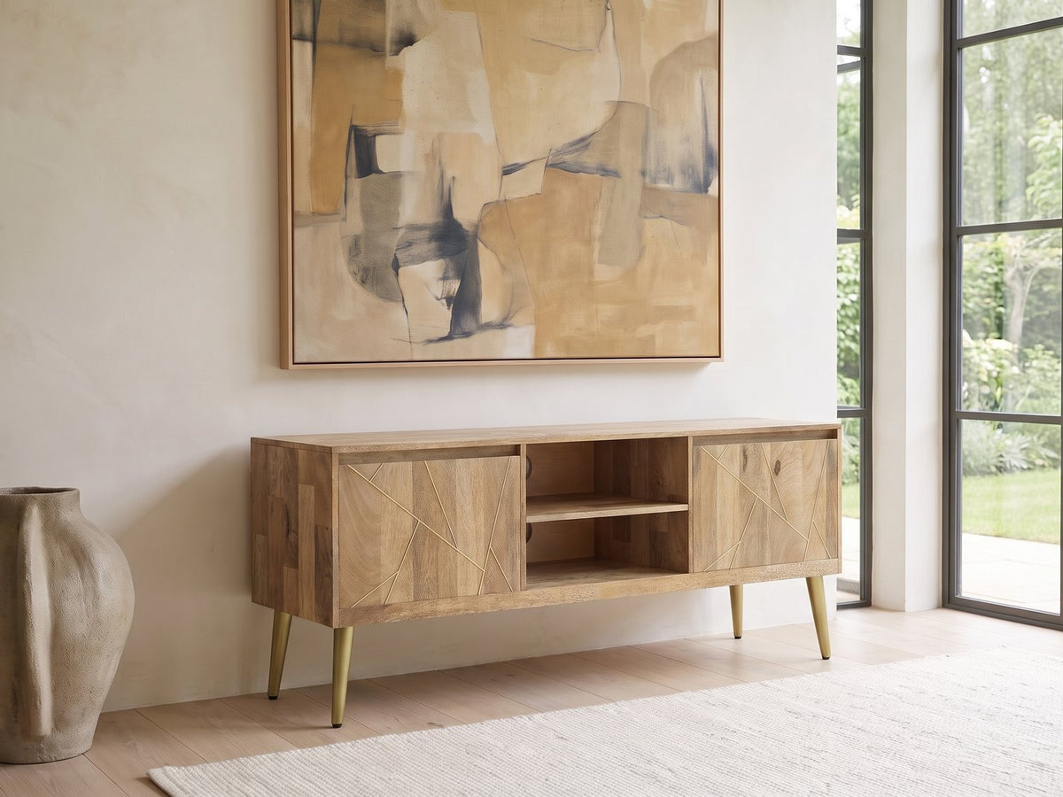 Monopoli Mango and Brass Media Console seen from the side, under a large abstract painting in a bright living room