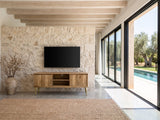 Monopoli Mango and Brass Media Console under a wall-mounted screen on a pale stone wall in a poolside villa