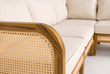 Close-up of a Monreale arm: the rounded acacia top rail and the open hexagonal cane weave, with the cream cushions behind