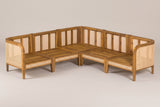 The five acacia frames of the Monreale sectional without cushions, pushed together into a V, with slatted seat decks and cane back panels