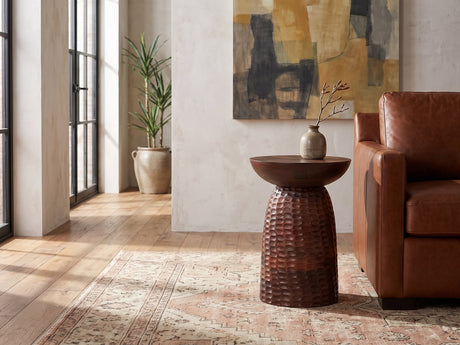 Montalbano Carved Mango Pedestal Side Table beside a leather sofa in an industrial loft