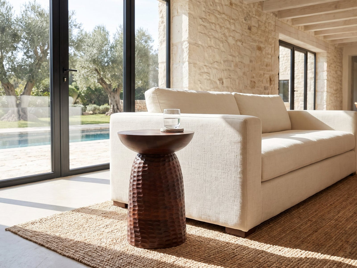 Montalbano Carved Mango Pedestal Side Table beside a linen sofa in a poolside villa