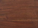 Close-up of the Montalbano Carved Mango Pedestal Side Table: the dark mango grain of the round top