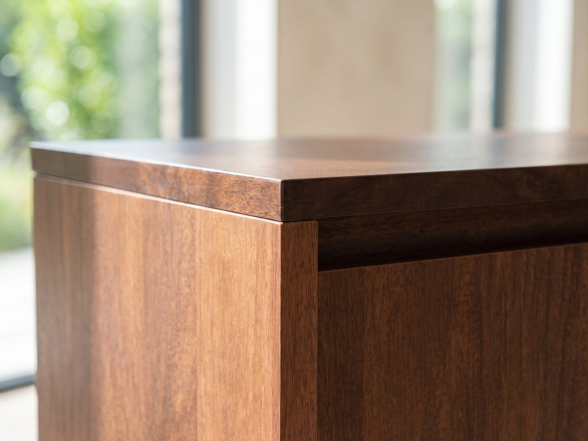 Close-up of the Montefalco Solid Mango Media Console: the top corner of the console: dark mango top and the door edge below