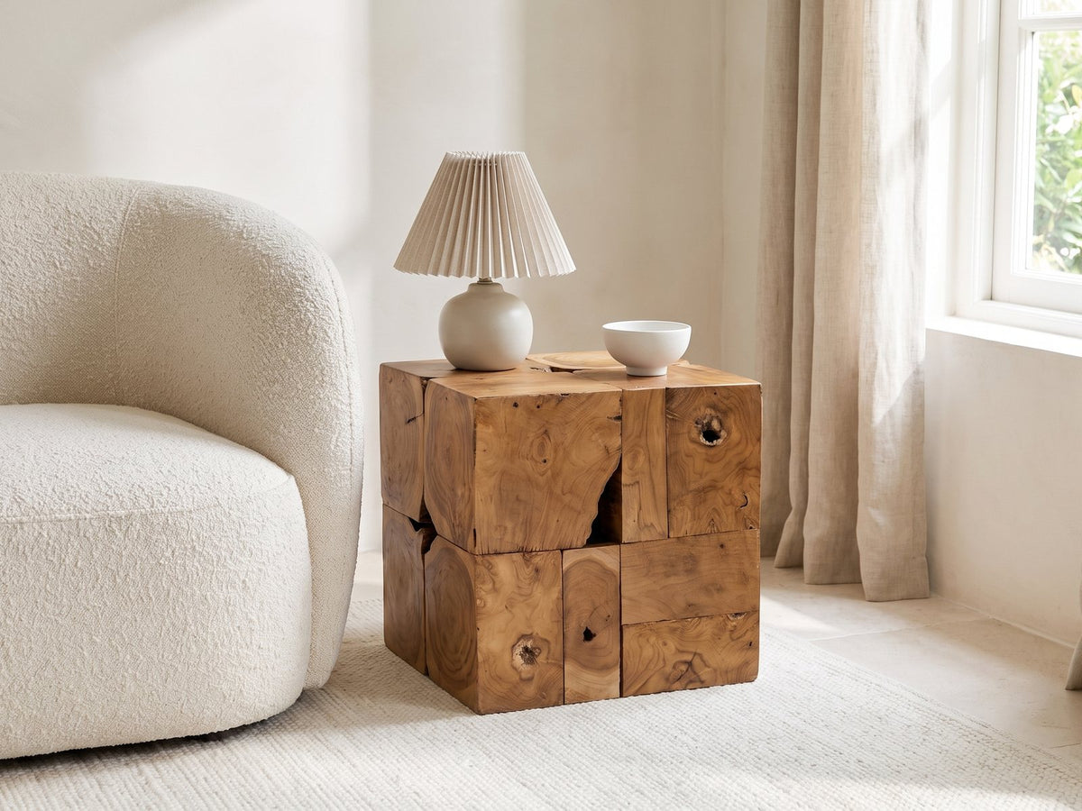 Montefiore Teak Root Cube Side Table with a lamp and a ceramic bowl beside a cream boucle armchair in a bright plaster room